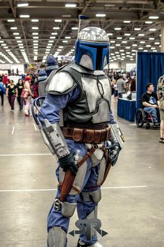 a man dressed as boba fett from star wars standing in a convention hall