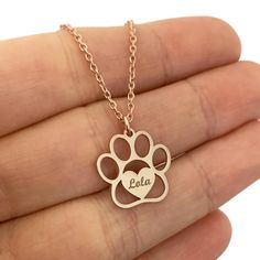 a person holding a dog's paw and heart necklace