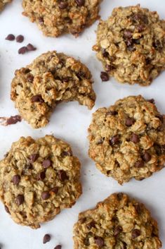 chocolate chip oatmeal cookies are arranged on a white surface with scattered chocolate chips