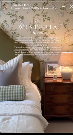 a bed with white sheets and pillows in front of a wallpapered headboard