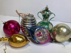 there are many different colored glass ornaments on the table together and one has a silver vase