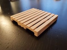 a small wooden shelf sitting on top of a black table next to a glass bottle