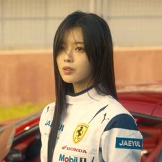 a woman with long black hair standing next to a red car