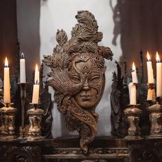 an ornate mask with candles in front of it