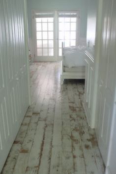 an empty bedroom with white walls and wood flooring on the floors, along with two doors leading to another room