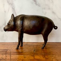 a statue of a pig standing on top of a wooden floor