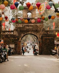 people are riding motorcycles under colorful lanterns on the bridge over the street in front of them