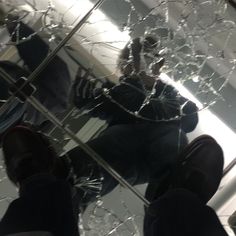 a person standing in front of a mirror with shattered glass on the bottom and bottom