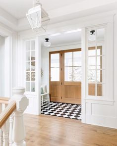 an entryway with wooden floors and white walls, wood trim around the doors and windows