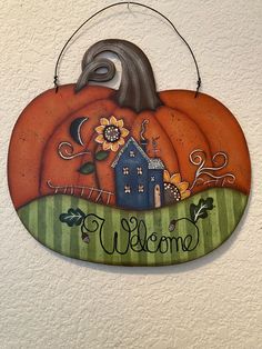 a welcome sign hanging from the side of a wall with a house and sunflowers on it