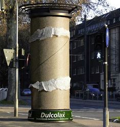 a pole that has some torn up paper on it in the middle of a street