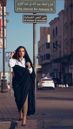 a woman is walking down the street wearing a black shawl