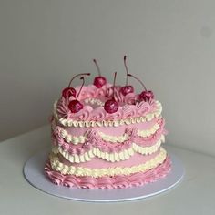 a pink and white cake with cherries on top