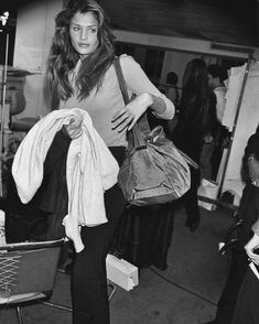 a black and white photo of a woman carrying bags