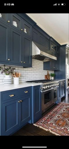 a kitchen with blue cabinets and an area rug in front of the stove top oven