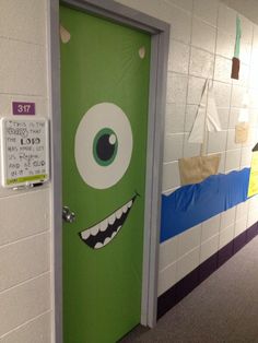 a green door with a monster face painted on it in a hallway next to a white wall