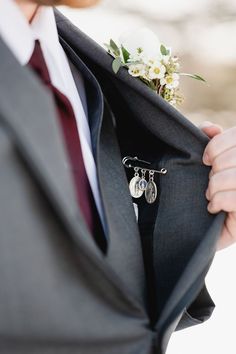 a close up of a person wearing a suit and tie with a boutonniere on his lapel