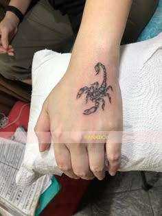 a small scorpion tattoo on the left hand