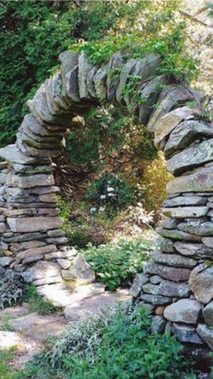 a stone arch in the middle of a garden