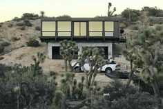 two cars parked in front of a house on top of a hill with palm trees