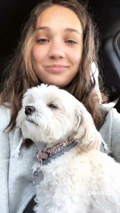 a woman holding a white dog in her lap