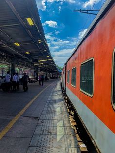 people are standing on the platform next to a train