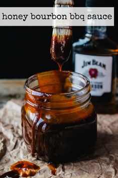 a jar filled with liquid sitting on top of a table next to a bottle of syrup