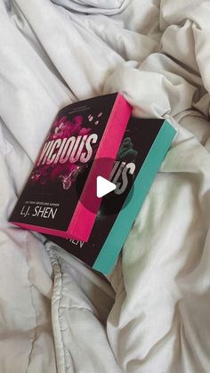 an open book laying on top of a bed covered in white sheets and blankets with the title vicious