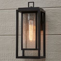 an outdoor light hanging on the side of a house with white siding and wood paneling