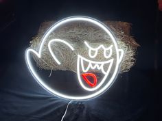 a neon sign with an evil face on it's head and tongue is lit up in the dark