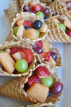 four cones filled with fruit on top of a table