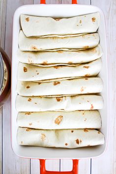 several tortillas in a white casserole dish