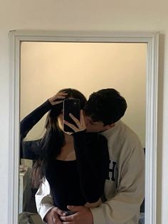 a man and woman taking a selfie in front of a mirror