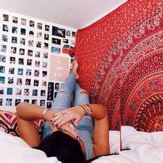 a woman laying on top of a bed next to a wall covered in pictures and photos