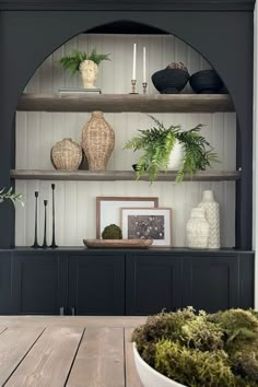 a wooden table topped with lots of plants and vases on top of bookshelves