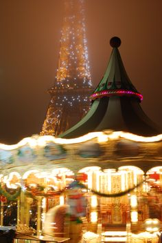 a merry go round at night with the eiffel tower in the back ground