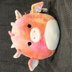 a pink and orange stuffed animal on the back of a couch with its eyes closed