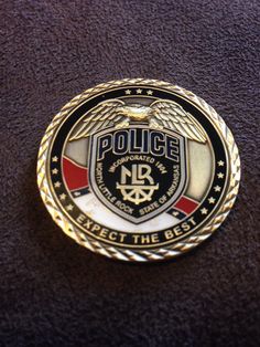 a police badge sitting on top of a brown table next to a black and white wall