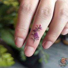 a woman's hand with a small flower tattoo on her left thumb and finger