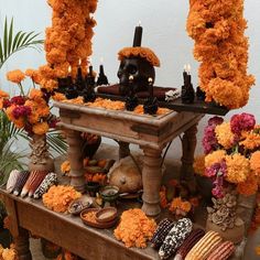 a wooden table topped with lots of flowers and candles covered in fake pumpkins on top of it