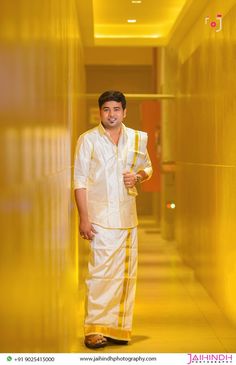 a man standing in a hallway with his hand on his hip wearing a white and yellow outfit