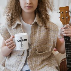 a woman holding a guitar and coffee mug