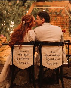 a man and woman are sitting on chairs with their backs to each other, kissing