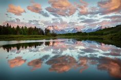 the sky is reflected in the still water of this lake as the sun goes down