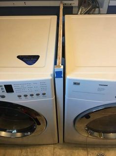 two washers sitting next to each other on the floor in front of a dryer