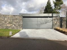 a modern house with stone walls and driveway