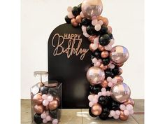 a birthday balloon arch with balloons on it and a vase full of flowers next to it