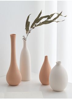 three vases with one plant in it and the other two are white, beige and pink