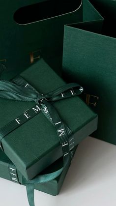 two green boxes with ribbons tied around them on a white surface next to each other