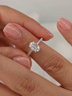 a woman's hand holding an engagement ring with a diamond on it and the other hand